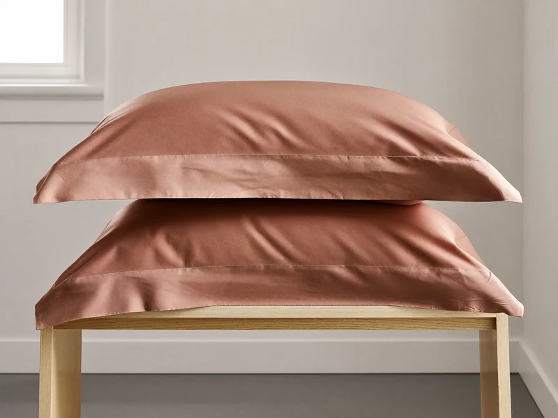 Coppia di federe in raso di cotone terracotta su una panca